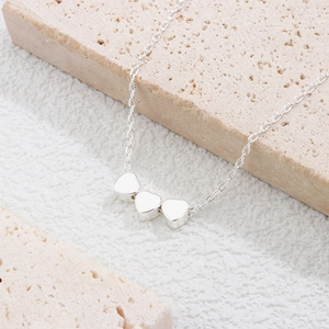 Detail showing three linked hearts on a 925 sterling silver chain over natural stone