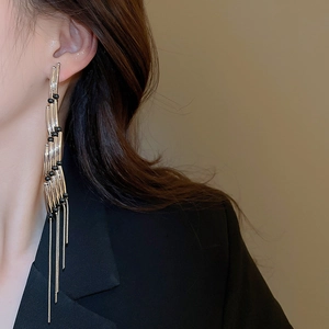 Silver rectangle tassel earrings with black beads worn by a model in a black suit
