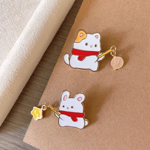 Détail de broches en émail représentant un chat et un lapin avec écharpes rouges