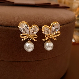 Vue macro de boucles d'oreilles nœud plaquées or avec zircons et perles blanches