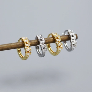 Macro detail of stacked gold and silver S925 huggie hoop earrings with sparkling zircons