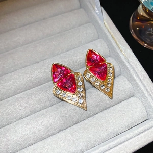Detail view of retro geometric diamond earrings with pink stones on a gold base