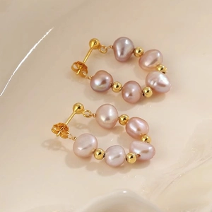 Macro detail of lavender baroque pearl earrings with golden beads in a circular design