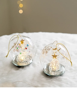 Close-up of glass Christmas angel and tree ornaments with glowing LED light and snowflake patterns
