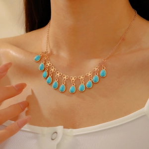 Detailed close-up of Bohemian gold necklace with twelve turquoise teardrop beads on a model