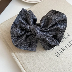 Close-up of a high-quality grey bow hair clip on a vintage book with soft lighting