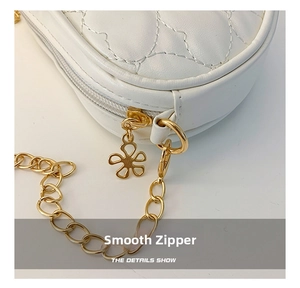 Detailed macro view of white quilted leather bag with floral gold zipper and chain strap