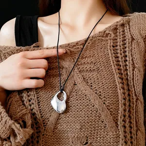 Minimalist silver hollow heart pendant necklace with black cord on knit sweater