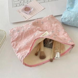 Detailed close-up of pink jacquard rose makeup bag with textured embroidery and zipper