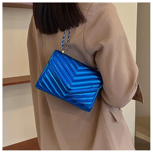 Blue patent leather crossbody bag with chevron quilting and chain strap on model
