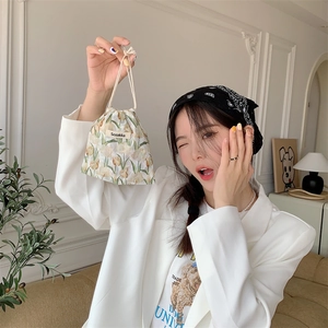 Detailed close-up of floral drawstring bag with elegant tulip patterns and brand label