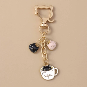 Detail of enamel black cat in coffee cup keychain with golden cat-shaped clasp