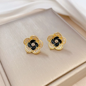 Close-up of camellia flower earrings with black enamel petals and micro-set zircons