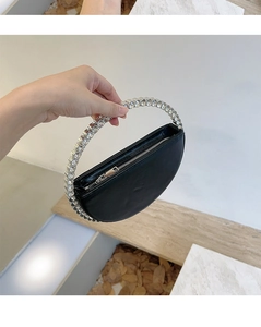 Detail of a crescent clutch bag with a crystal-encrusted circular metal handle