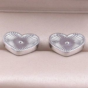 Close-up of heart-shaped 304 stainless steel earrings with radial texture on silk background