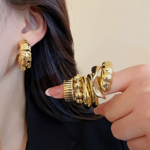 Detailed view of vintage gold ring set and hammered earrings on model in soft light