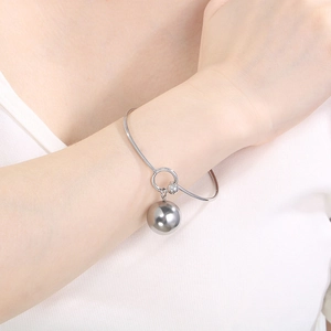 Close-up of a minimalist silver metal ball pendant bracelet worn on a female wrist