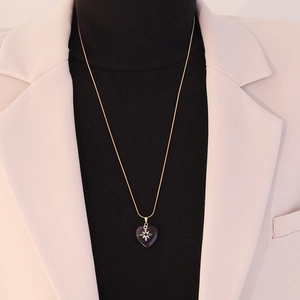 Macro shot of gold heart pendant necklace with star motif on a mannequin neck