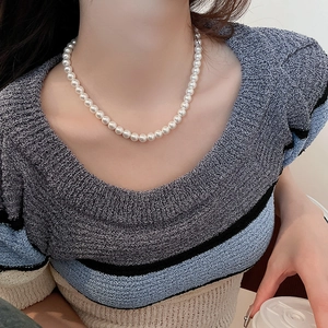Close-up of elegant pearl necklace on model's neck for a stylish minimalist look