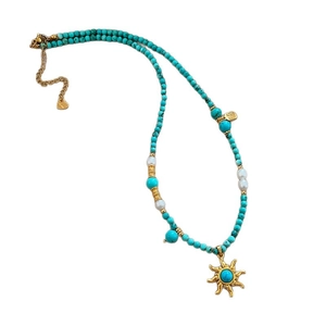 Collier vintage en perles de turquoise avec pendentif soleil et accents dorés sur blanc