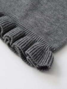 Detail showing the gray knitted fabric texture and elegant wavy lettuce edge design