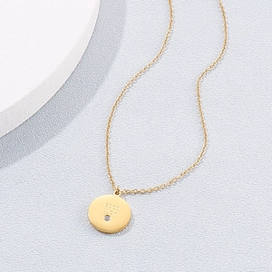 Détail d'un pendentif rond doré gravé Good Luck avec un petit diamant incrusté