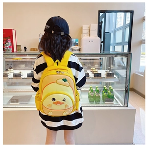 Close-up of yellow cartoon duck backpack for kids with mesh pocket in a cafe setting
