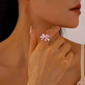 Close-up of handmade floral beaded ring with purple resin petals and green glass beads