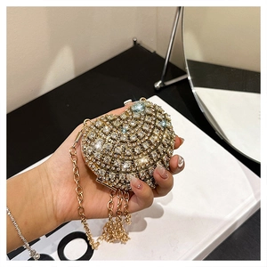 Détail de la pochette de soirée cœur dorée avec strass scintillants et pompons en chaîne