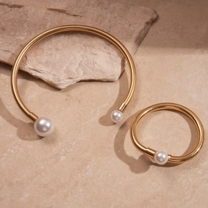 Detail of gold pearl choker and bracelet set displayed on elegant marble and natural stone
