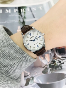 Close-up of a women's watch with brown leather strap and dual calendar display feature