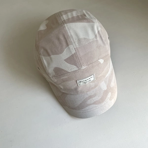 Detail of 5-panel camo baseball cap with woven label, metal eyelets and cotton twill texture