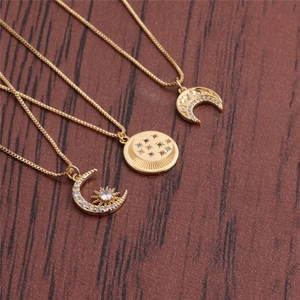 Détail de trois colliers dorés avec pendentifs lune et étoile en zircon sur bois sombre