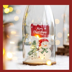 Close-up of decorative glass bottle with snowman and glowing warm LED light string