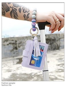 Detail of purple silicone beaded wristlet with leather card holder and tassel on luggage handle