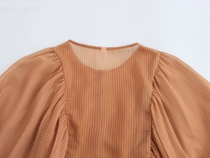 Detail der orangefarbenen Streifenbluse mit transparentem Netzeinsatz und Puffärmeln