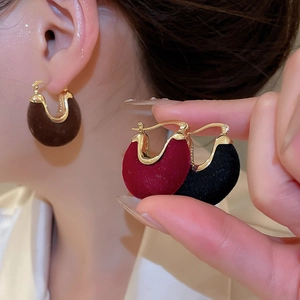 Detailed view of U-shaped velvet earrings in brown red and black with gold frame