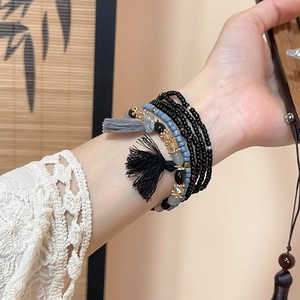 Detail view of multi-layer Bohemian beaded bracelet with blue crystals and grey tassel charm