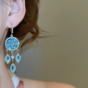 Detailed shot of gold drop earrings with blue star crystals and dangling teardrop gems
