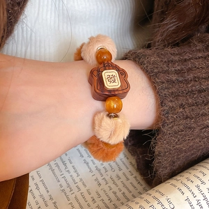 Gros plan d'un charme pelucheux et d'un pendentif en bois avec caractère gravé doré sur le bracelet