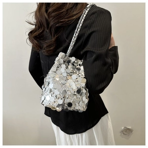 Elegante borsa a secchiello con paillettes argento e catena metallica, indossata da modella
