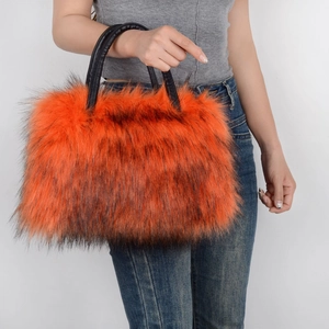 Close-up of orange faux fur tote bag featuring black leather handles and dark tipped texture