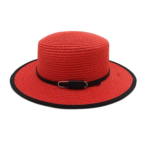 Détail d'un chapeau canotier rouge en paille avec bordure noire et boucle en métal chic