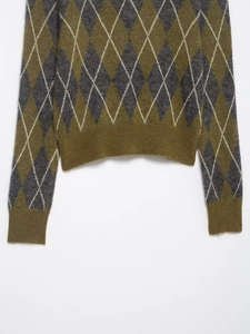 Detail view of argyle diamond pattern and ribbed hem on a knitted polo sweater