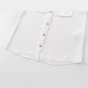 Close-up of white padded shoulder shirt with four metallic textured buttons