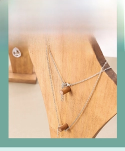 Detail view of smooth natural wood necklace display stand with dual hanging pegs