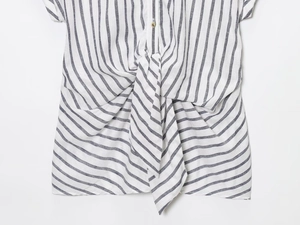 Dettaglio dell'orlo annodato su una camicia a righe grigie e bianche in lino