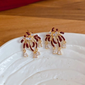 Detailed macro view of gold-plated firework earrings with red enamel and clear zircons