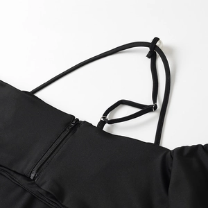Detail of black fabric featuring metal zipper closure and white pearl decorations
