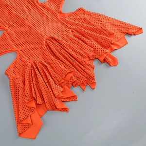 Détail d'une robe orange à strass avec volants étagés et ourlet asymétrique